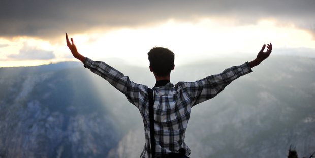 Student standing at top of mountain watching sunset